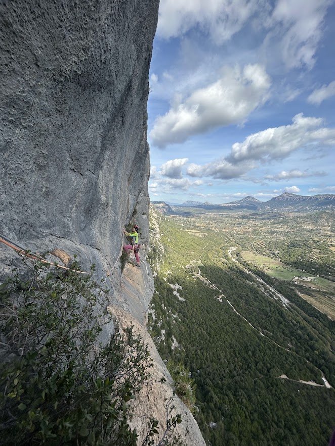 Traversing a rock face above a green valley